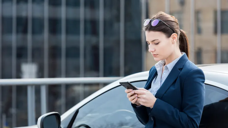 Woman with the phone standing by the car